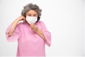 Older woman using a face mask to remain protected.